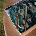 Gold paperclip on a magazine with a nature-themed cover on a wooden surface.