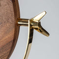 Wooden mirror with a gold metal handle on a light gray background