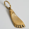 Gold foot-shaped pendant on a light gray background