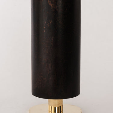Black cylindrical vase with brass base on a light gray background