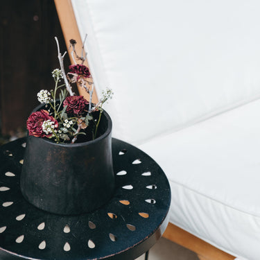 Black pot with dried flowers on a decorative table against a white sofa.