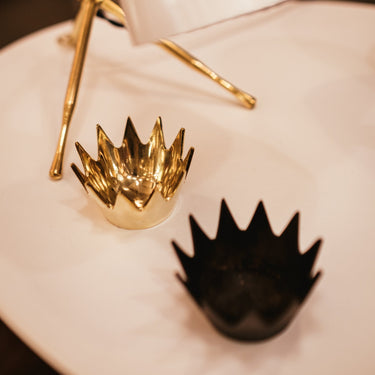 Gold and black crown-shaped objects on a white surface
