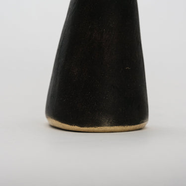 detail of cone-shaped brass bookend on a light gray background