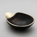 Black brass bowl with gold interior on a gray background