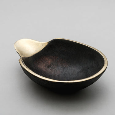 Black brass bowl with gold interior on a gray background