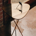 Wooden Aubock stool with a unique design on a textured floor.