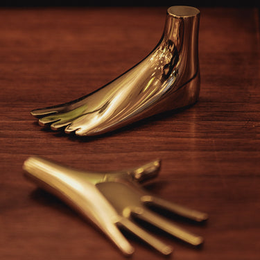 aubock hand and foot paperweights in brass on wood table
