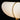 Close-up of a lamp with white shade and gold base on a black background