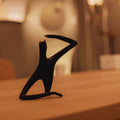Black abstract sculpture on a wooden surface with a blurred background