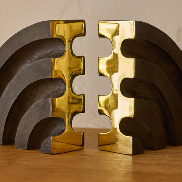 solid brass rainbow bookends by carl aubock on a wood shelf