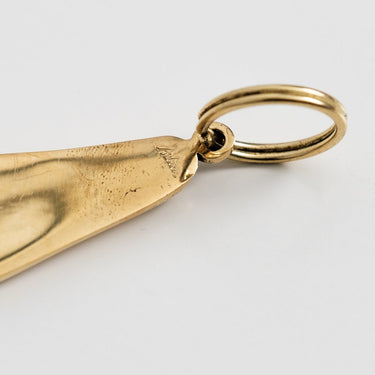 Gold foot-shaped pendant on a light gray background