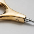 Close-up of a gold tool with a brand name on a light gray background