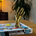 Gold hand sculpture on a wooden surface with a box labeled 'Surrealism' in the background.
