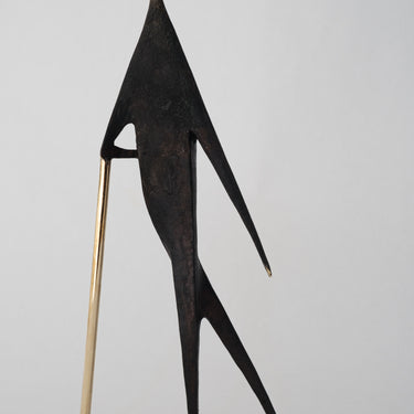Abstract sculpture of a figure with a long neck and thin legs on a light gray background