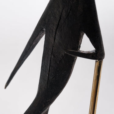 Black abstract sculpture with a gold base on a white background