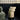 Beige cylindrical side table with a lid in a modern room with glass block windows.