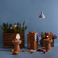 Decorative setting with flowers, candles, and small table lamps against a blue wall.