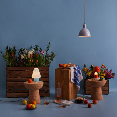 Decorative setting with flowers, candles, and small table lamps against a blue wall.