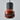 Ceramic pendant light with red base and black textured top on a gray background