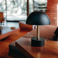 Black table lamp on a wooden surface with a blurred indoor background