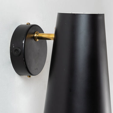 Black wall-mounted lamp with gold accent on a white background
