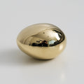 brass egg on a light gray background