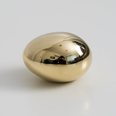 brass egg on a light gray background