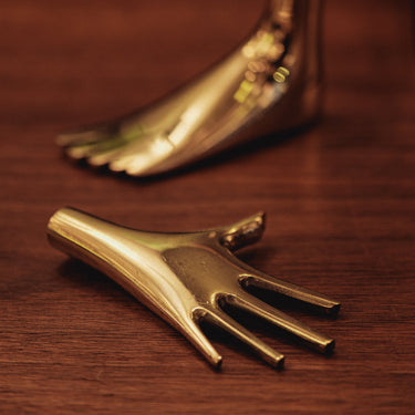 Gold foot and hand sculpture on a wooden surface