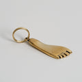 Gold foot-shaped keychain on a light gray background