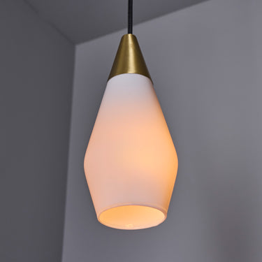 Two glass pendant lights similar to tynell or mauri almari with brass accents on a grey background detail of shade