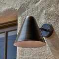 bronze painted wall light midcentury style against a sunny stucco wall