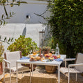 Outdoor patio setting with a table, chairs, and a meal setup on a sunny day.
