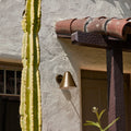 Brown wall light at doorway of spanish style los angeles home with cactus and red tile roof