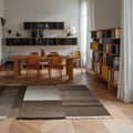 Modern interior with a dining table and chairs in a room with perriand bookcase mouille lamps and a large window on a brown rug