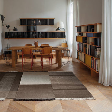 Modern interior with a dining table and chairs in a room with perriand bookcase mouille lamps and a large window on a brown rug