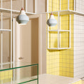 Modern bathroom interior with yellow tiles, glass shelves, and grey pendant lights.