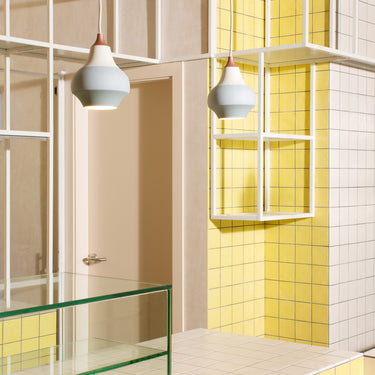 Modern bathroom interior with yellow tiles, glass shelves, and grey pendant lights.