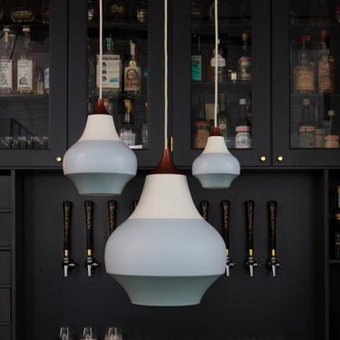 Modern pendant lights hanging above a bar with dark cabinets and beer taps.