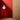 White cirque pendant light hanging against a red wall with a wooden floor and curtain.