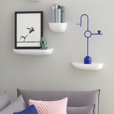 Gray sofa with colorful cushions against a light gray wall with vitra shelves and decor