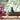 Decorative vitra house bird in black ash and a purple plant on a windowsill with a blurred green outdoor background