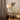 Modern interior with a side table, lamp, and chair against a neutral wall.