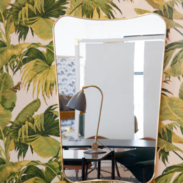 GUBI fa ponti mirror in polished brass on a palm printed wall