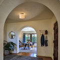Archway leading into a dining room with a gray rug on the wooden floor and glass ceiling light