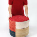 Person sitting on a colorful ottoman with a white background