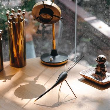 Collection of decorative items including a tall cylindrical object, a small round item, and a tall metallic object on a wooden surface.