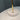 Close-up of a light fixture with a gold arm and white shade against a gray background.