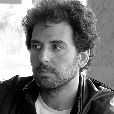 Black and white portrait of designer Marcos Catalan with a beard and tousled hair.