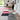 Woman standing in a modern room with colorful rugs and a white chair.