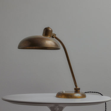 Bronze brass lariolux desk lamp on a white surface with a gray background